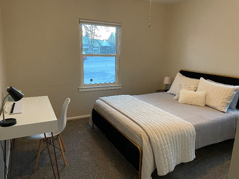 Bedroom #1 with queen bed and desk. Both windows in room have blackout shades