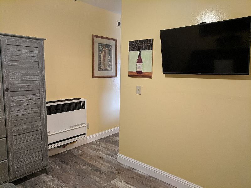 View of bedroom armoire and efficient, wall-mounted gas space heater.