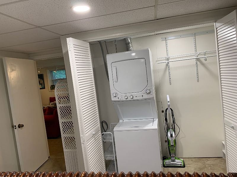 Large closet with washer/dryer stack in unit, iron and ironing mat, vacuum cleaner, Swiffer, starter cleaning supplies and detergent provided.