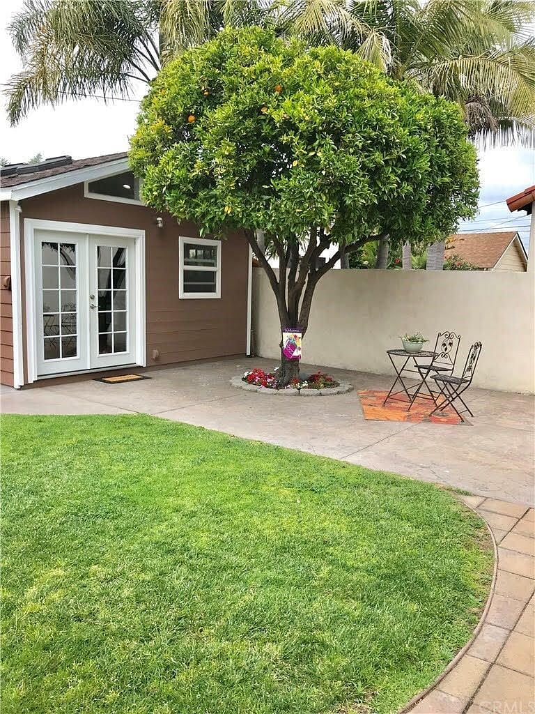 Private Guest House with main entrance and patio beneath a lush orange tree.