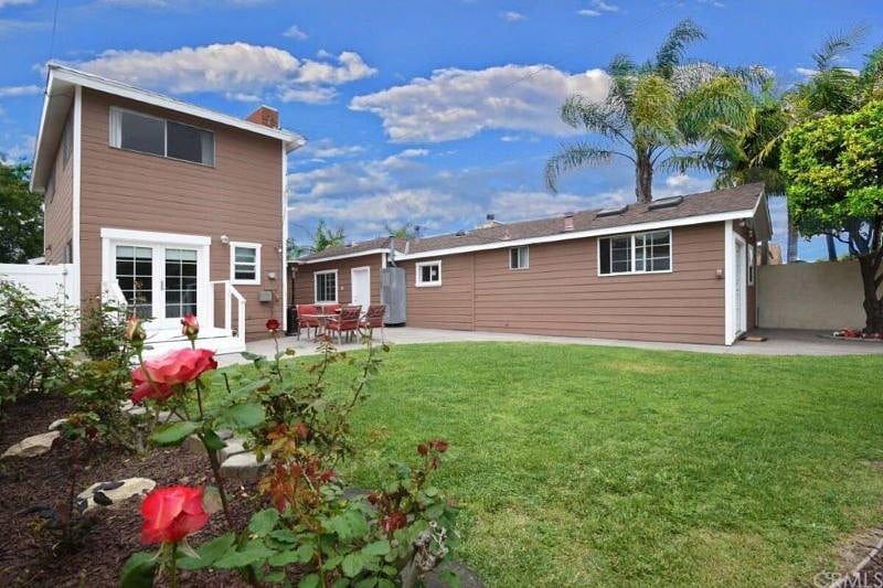 A view of the guest house (right), yard, and front house (left) from the rose garden.