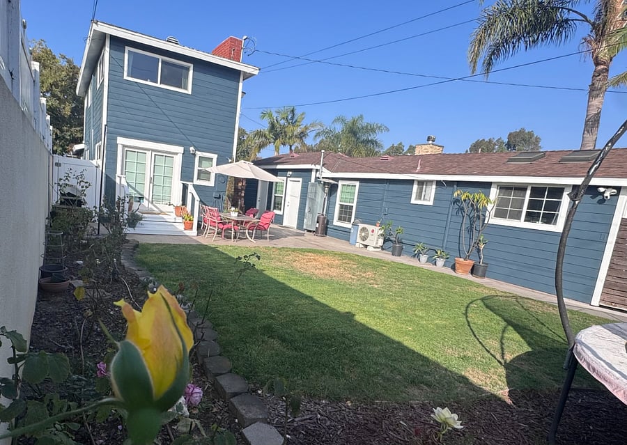A view of the guest house (right), yard, and front house (left) from the rose garden.