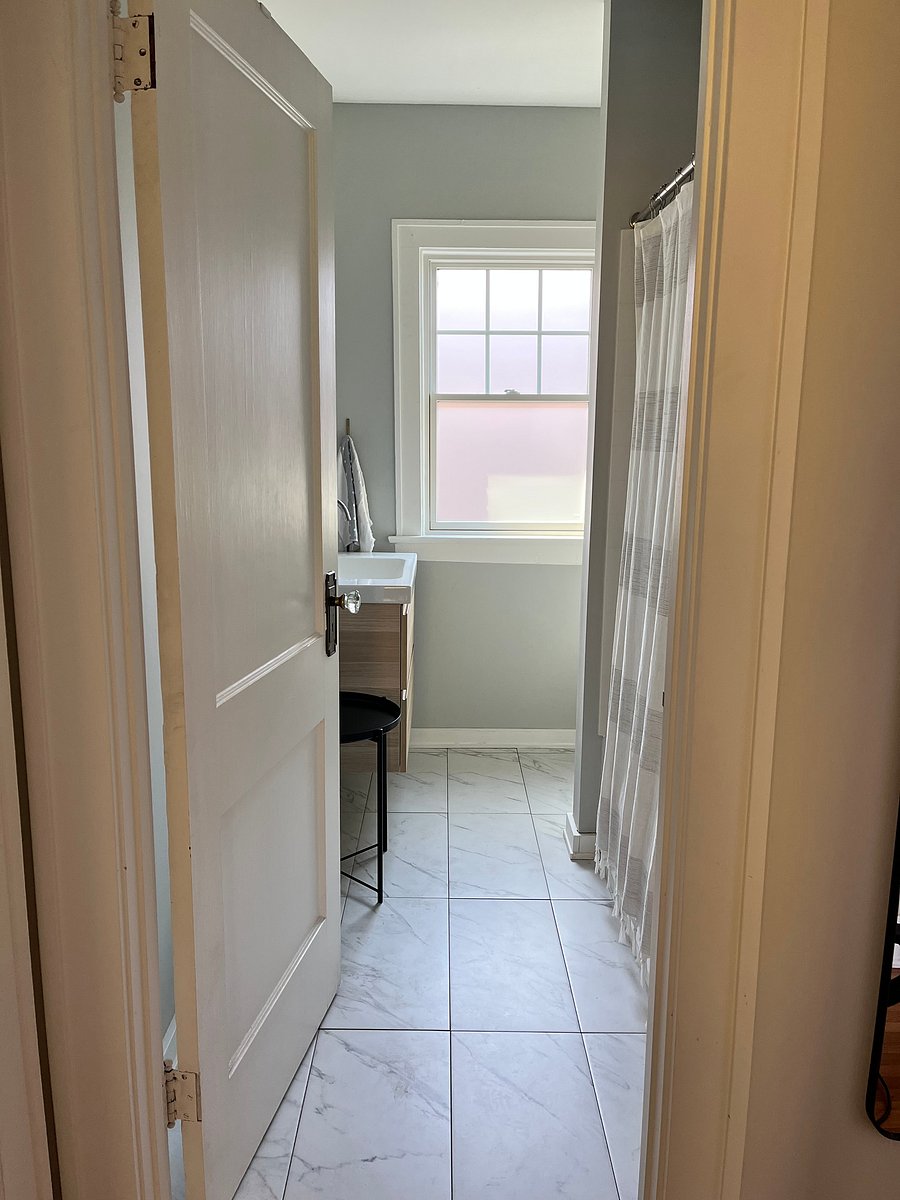 Bathroom with shower and bathtub unit, vanity and storage medicine cabinet. Frosted window in the bathroom that allows light but ensures privacy.