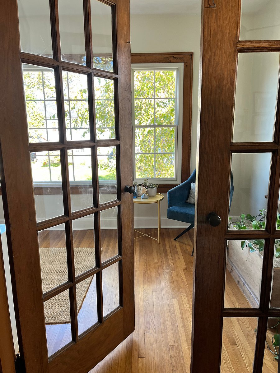 French doors off of living room to enter reading/sunroom with daybed and book cabinet.