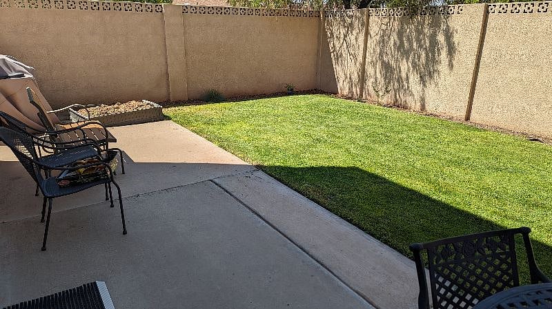 Backyard with BBQ grill, seated areas, and fully enclosed.
