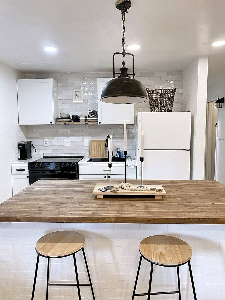 Full kitchen with sink, stove, microwave and fridge. Island has two barstools