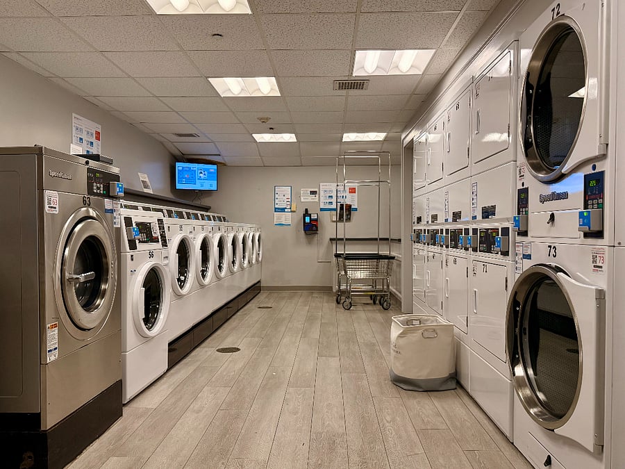 Sparkling clean laundry room with many machines, open 24/7. An app informs users of machine availability, and when cloths are finished!