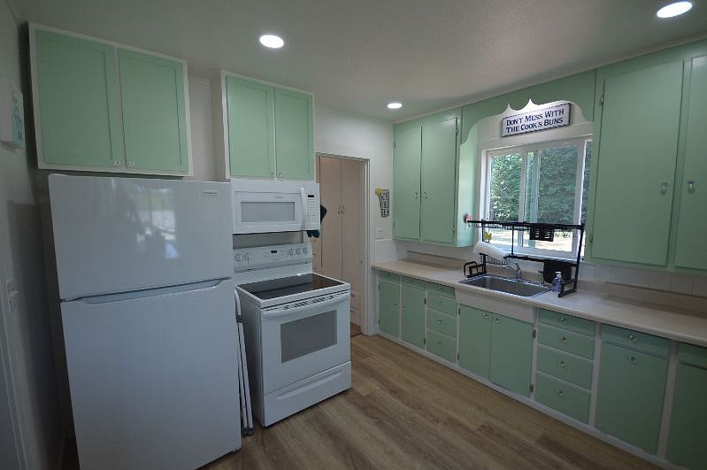 Electric range and dish drying rack over sink. Lots of cabinets for storage.