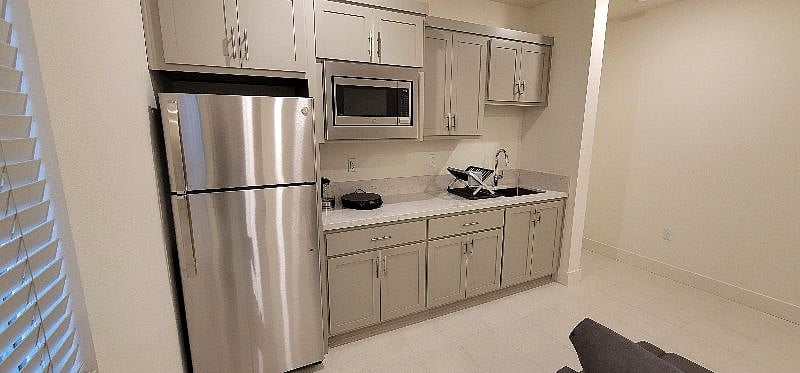 Kitchenette with microwave and electric oven combination, refrigerator with freezer, 8" cooktop, fullsize kitchen sink, and cabinet space.