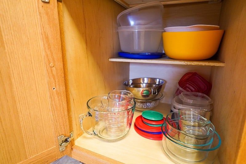 Large cookings bowls, food storage containers, and measuring bowls located in bottom cabinet next to coffee bar.