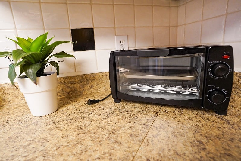 Toaster oven found on corner counter near sink.
