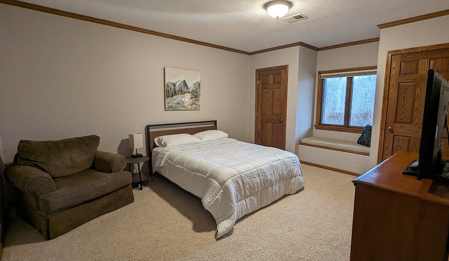 Bedroom 1 with a queen bed, two closets, dresser, TV, comfy chair and a window seat (with storage underneath).