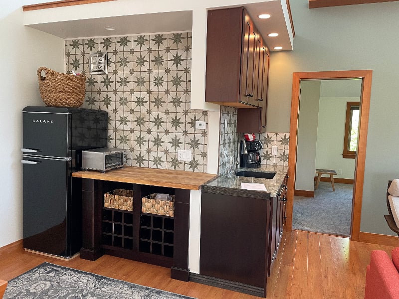 There is a 3/4 retro refrigerator, Breville toaster over, a two-burner inductive cooktop, a one to 10-cup coffee maker, and a microwave station that includes a tea kettle.