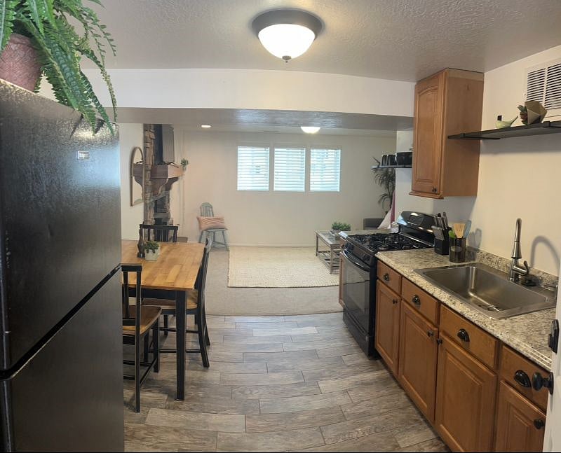 Full kitchen with garbage disposal, dishwasher, cabinet and shelve space, wood table, and gas stove.
