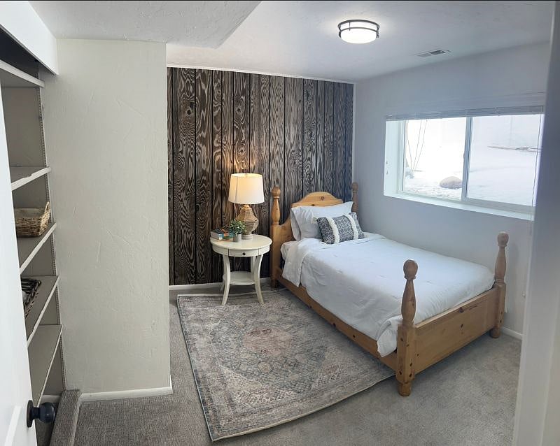 Twin bed in guest bedroom with closet rack and and shelving. View of private fenced in backyard.