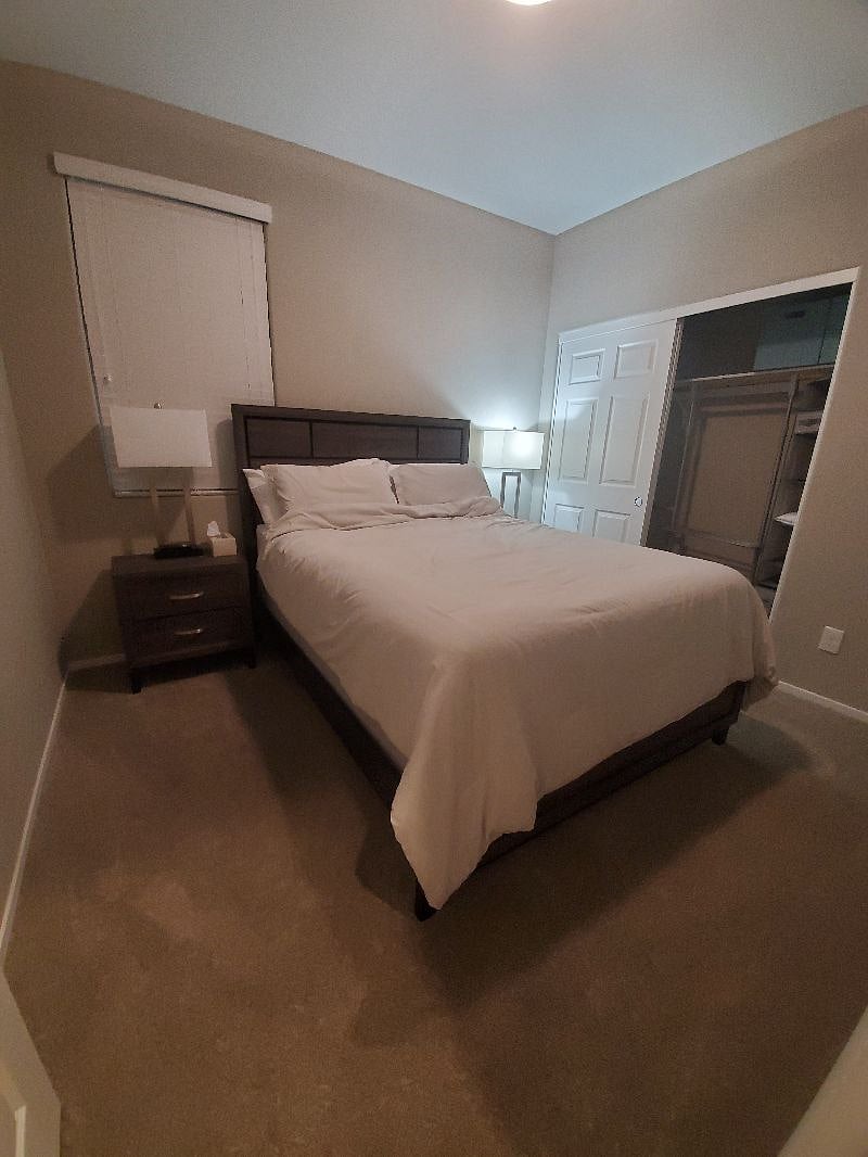 Bedroom with queen sized bed, nightstands, lamps, smart TV.