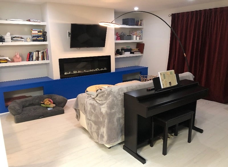Living room with multiple seating options, smart TV with various apps, electric fireplace, and digital piano.