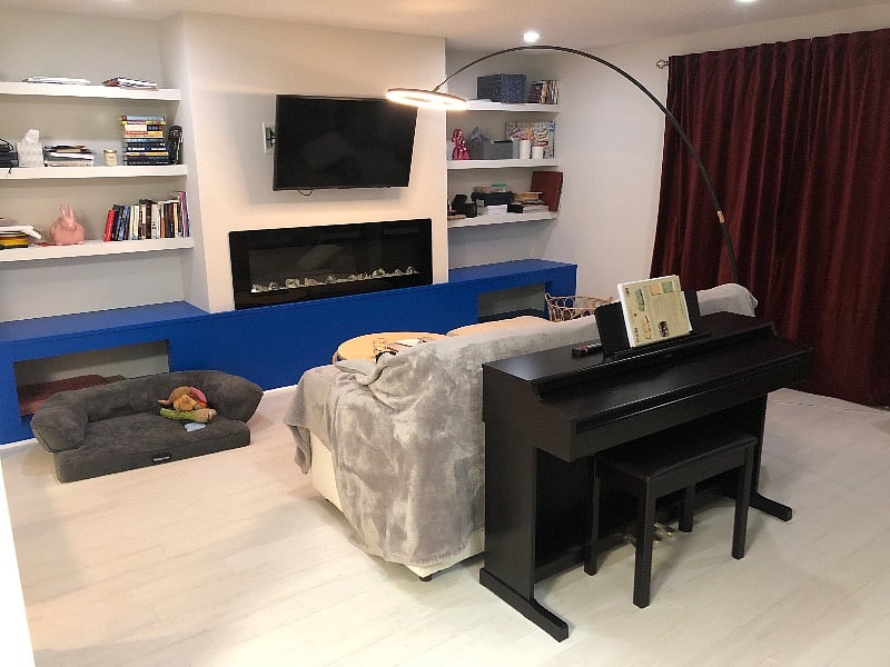 Living room with several sitting options, a smart TV with apps, electric fireplace, and digital piano.