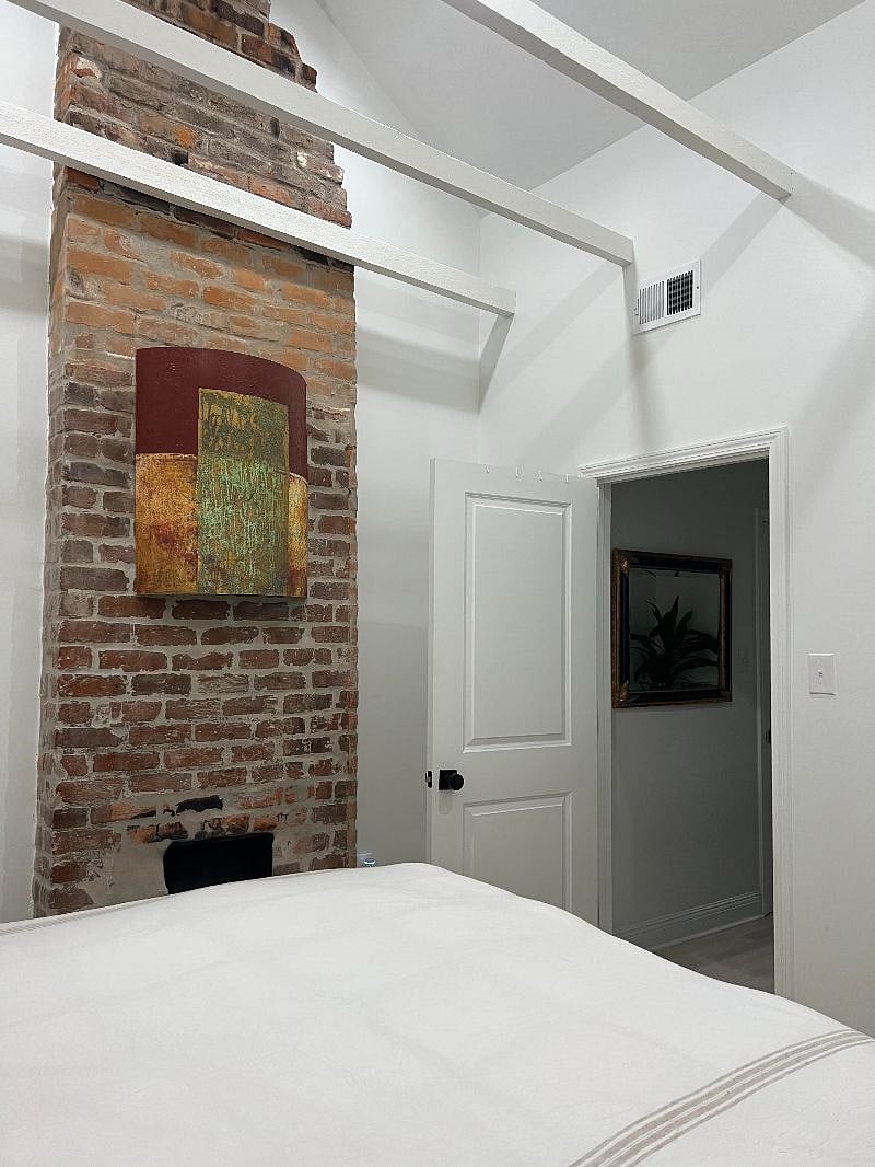 Bedroom with decorative brick chimney and vaulted ceilings