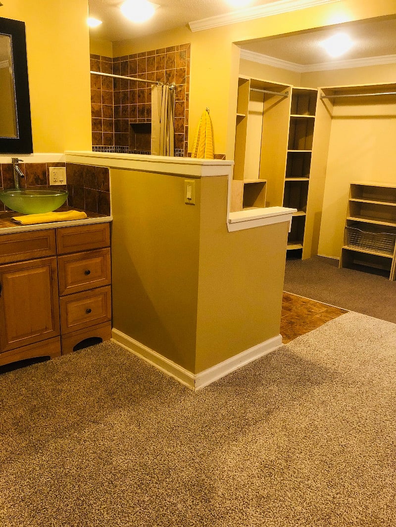 Master bathroom with an open walk-in shower, open vanity and open closet space.