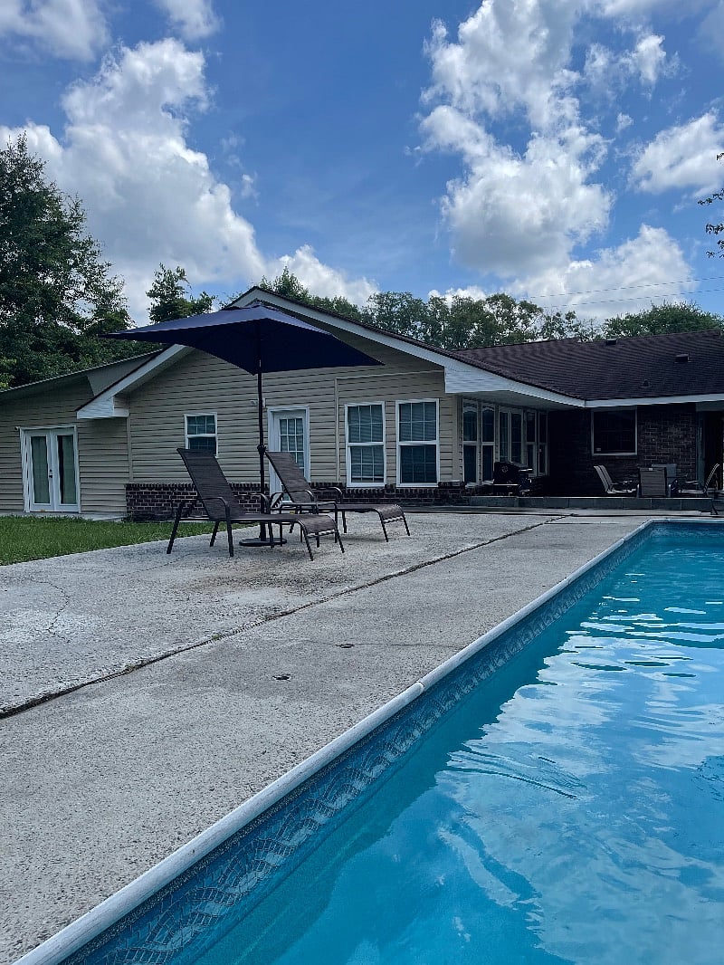 back of the house with a small caption of the swimming pool and the outdoor patio.