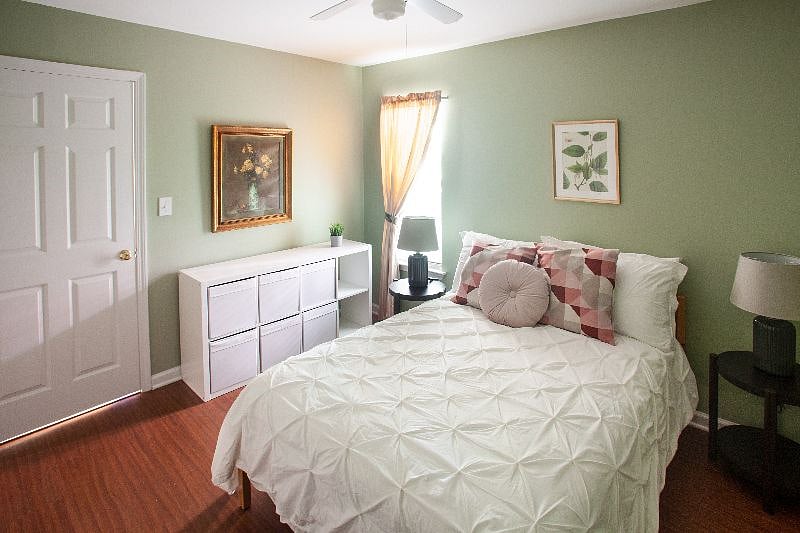 Main bedroom with queen sized bed and light blocking curtain, window looking out on greenery.