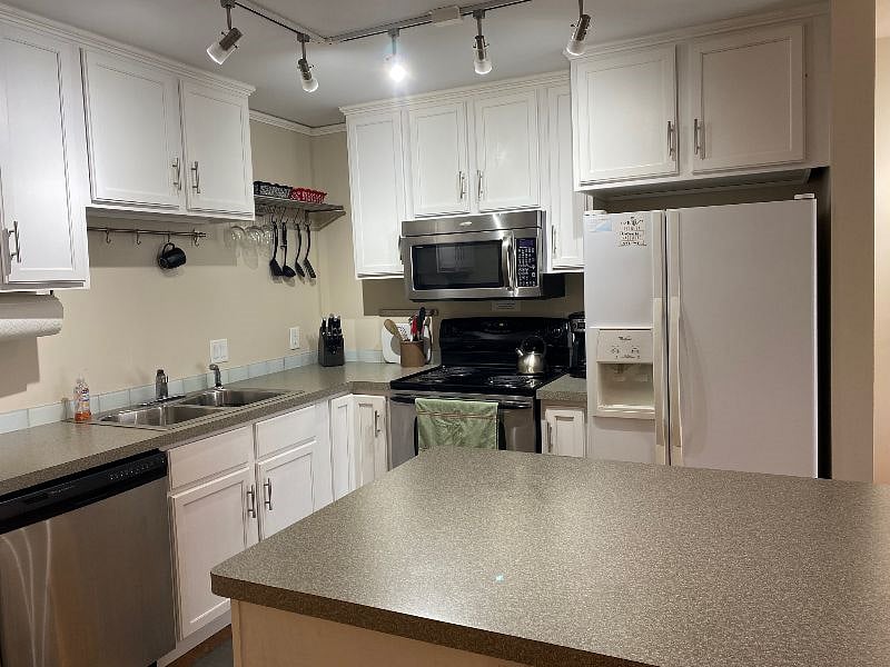 An electric stove/oven with over the range microwave oven is next to a side-by-side refrigerator-freezer with an external water dispenser.