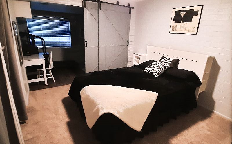 Back Bedroom With Barn Doors Leading To Work Space, Treadmill, And Full Size Washer and Dryer.