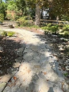 Fenced private backyard patio with stone walkway and fire pit (upper left corner).