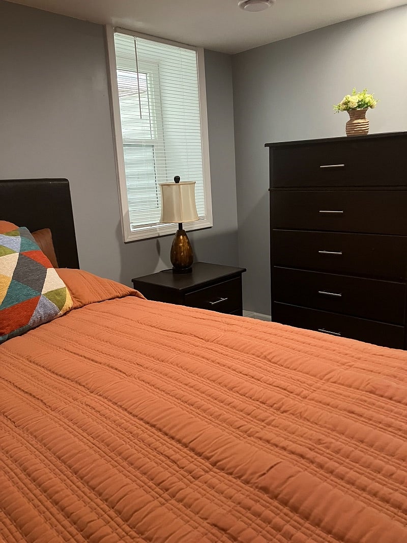 Comfortable queen-sized bed, with bedding, nightstand and chest.