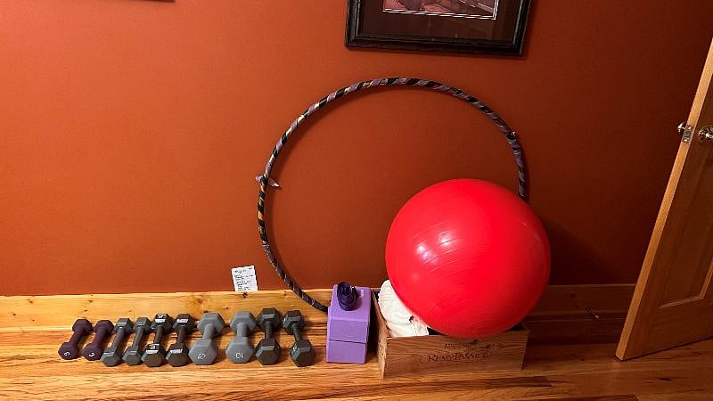 Workout equipment including weights, yoga mat, ball, hula hoop.