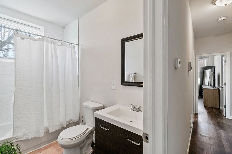 The shared bathroom with a full shower, bath tub, and vanity.