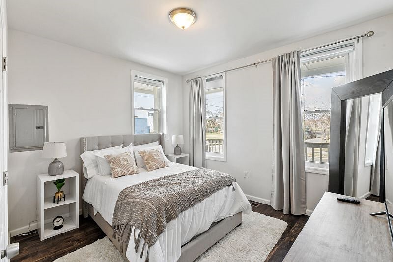 The Primary Suite features a Queen bed with farmhouse-style furnishings, a full mirror, and incredible natural lighting!