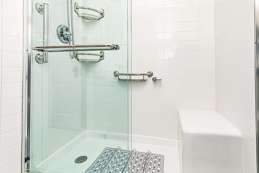 Walk-in shower with handrails and built-in seating.