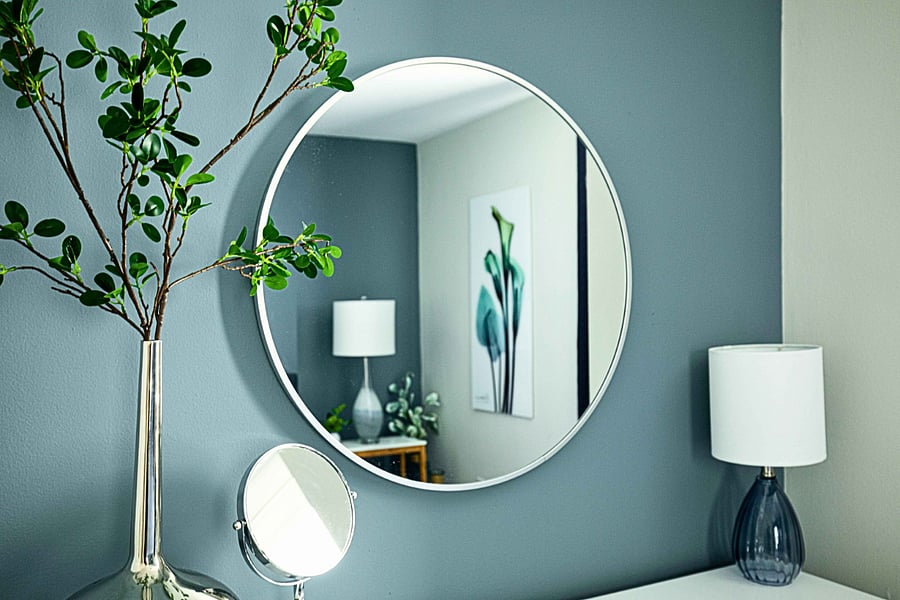 Beautifully styled bedroom with a large round mirror and curated decor.