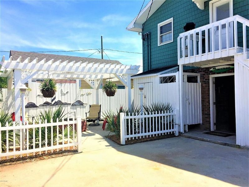 Parking for upstairs unit adjacent to house entrance and pergola area.