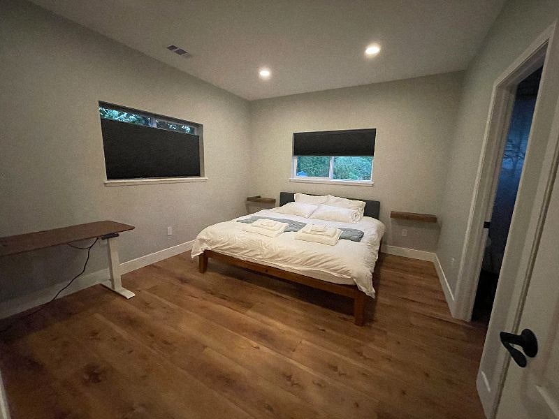 Bedroom 1 with shades closed and lights on. Each bedroom has a motor-operated standing desk for your work from home needs.