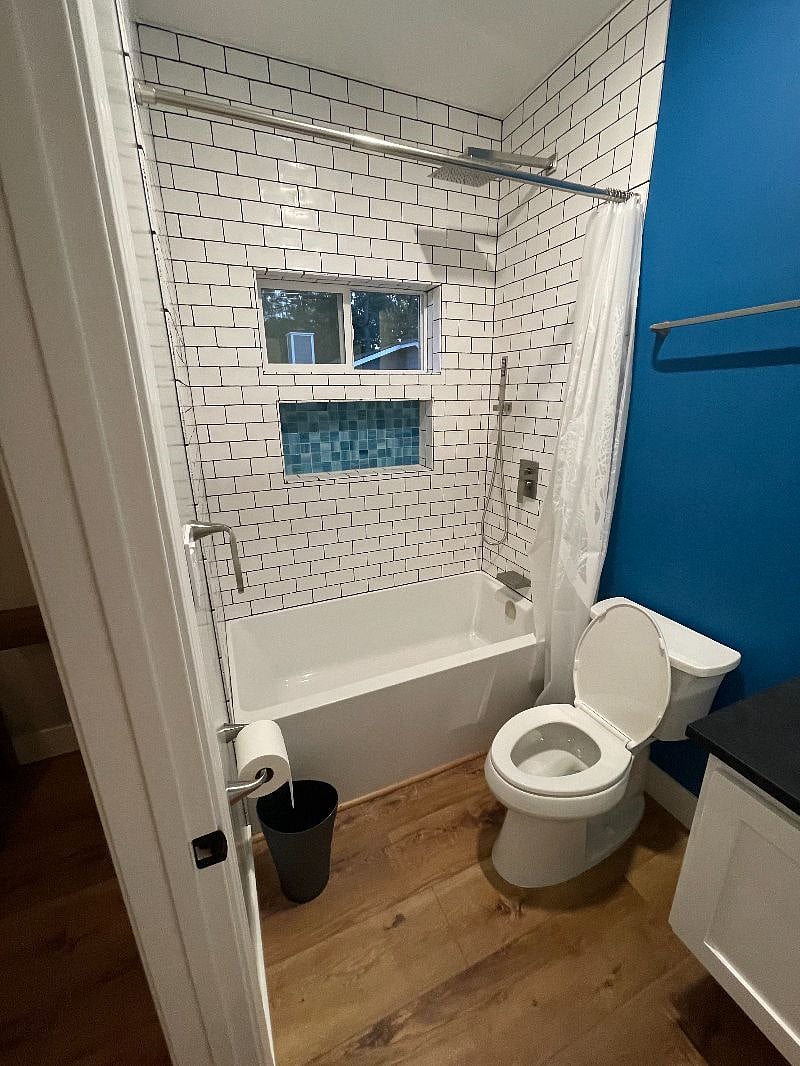 Bathroom 1 with deep blue accent wall and oversized ledge inside shower for all your product storage needs.