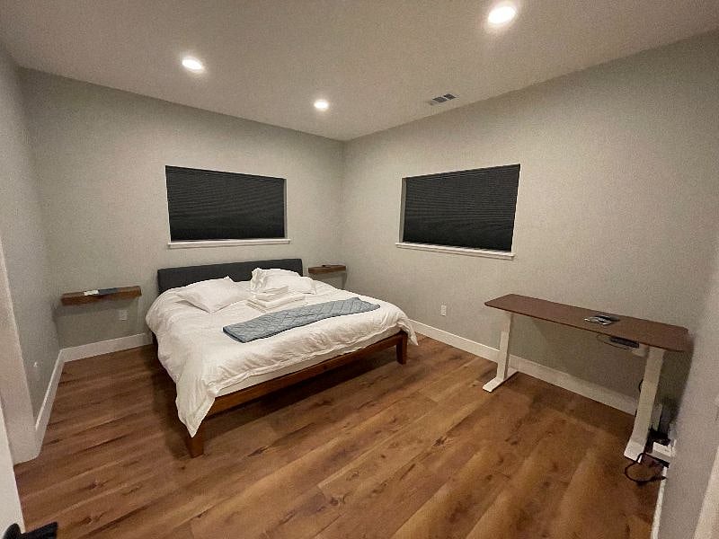 Bedroom 2 with shades closed and lights on. Each bedroom has a motor-operated standing desk in case you need to work from home.