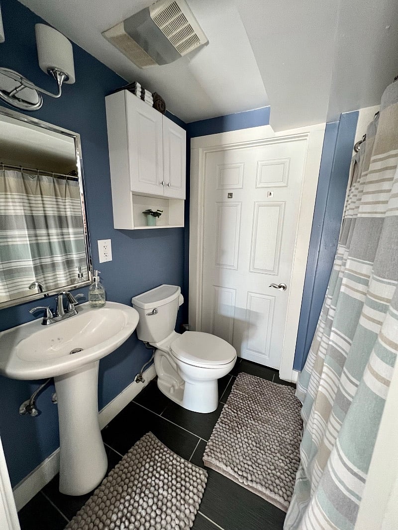 Freshly painted bathroom with new floor mats, linens, and towels that leads to the laundry room.