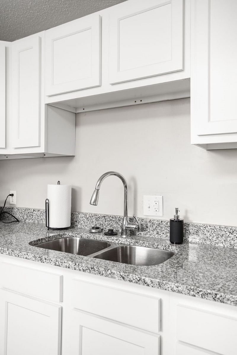 Sleek and modern kitchen sink area with a dual-basin stainless steel sink, granite countertops, a stylish pull-down faucet, and minimalistic decor for a clean, contemporary look.