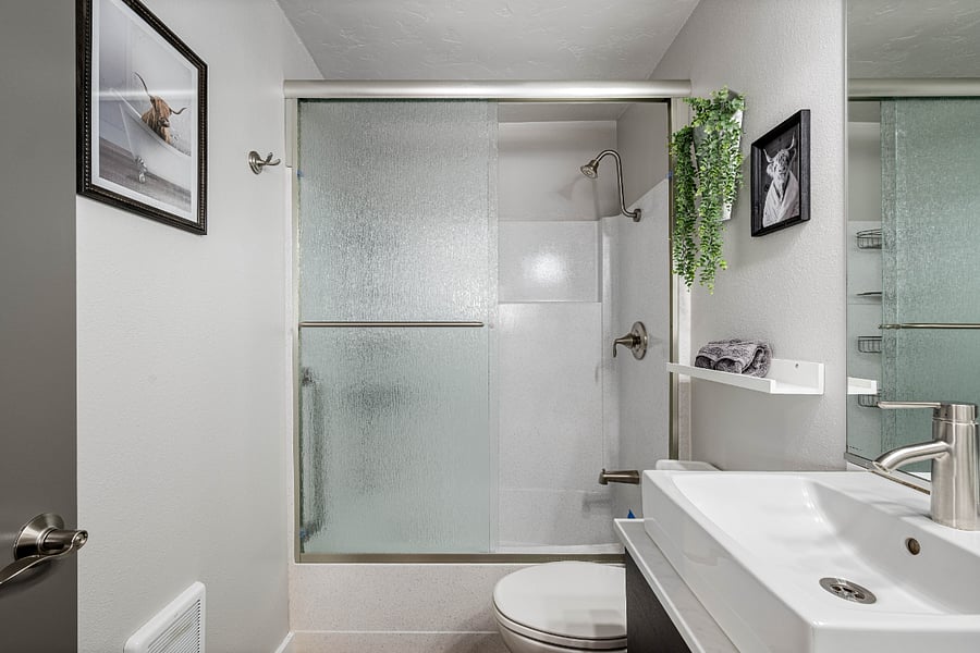 Bathroom with glass sliding shower door, toilet and vanity