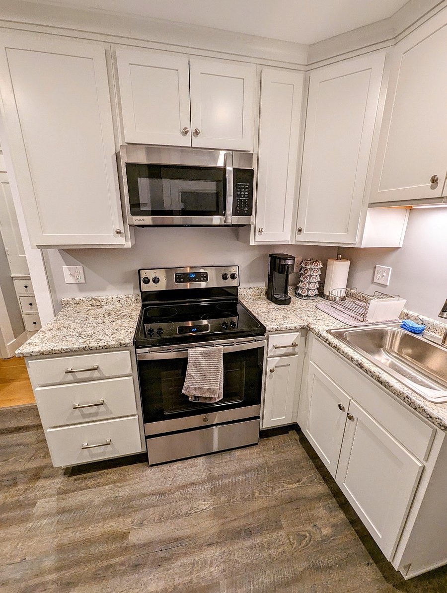 Kitchen with microwave, electric range, refrigerator, sink, plenty of cabinet space, and dining area.