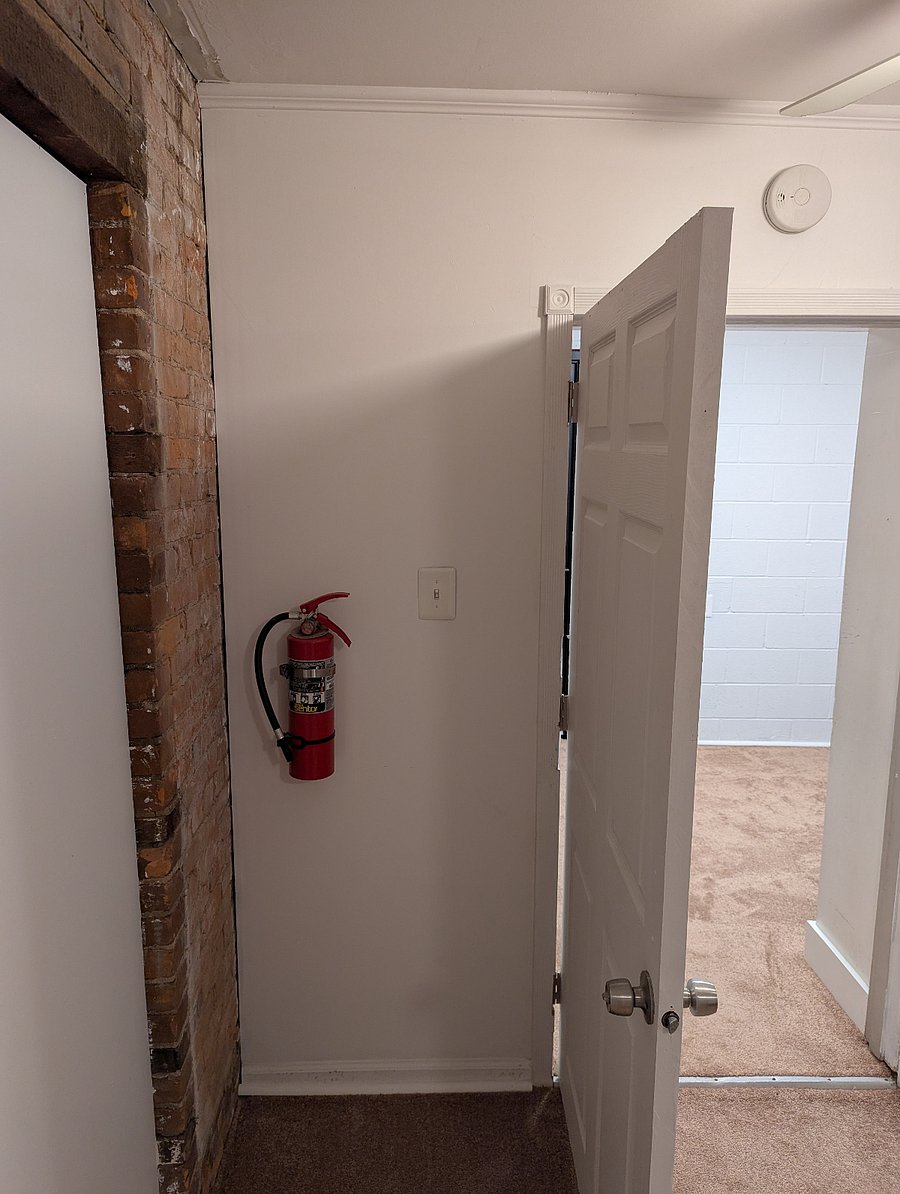 Fire extinguisher and light switch behind bedroom door