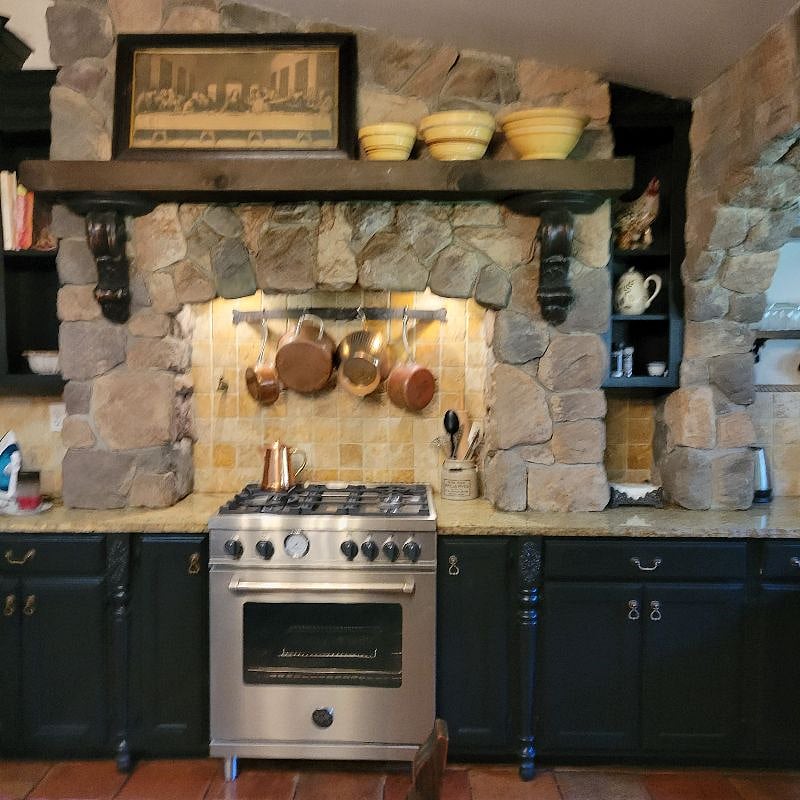Beautiful Italian stove and copper pots  and stone surround are featured in this photo.