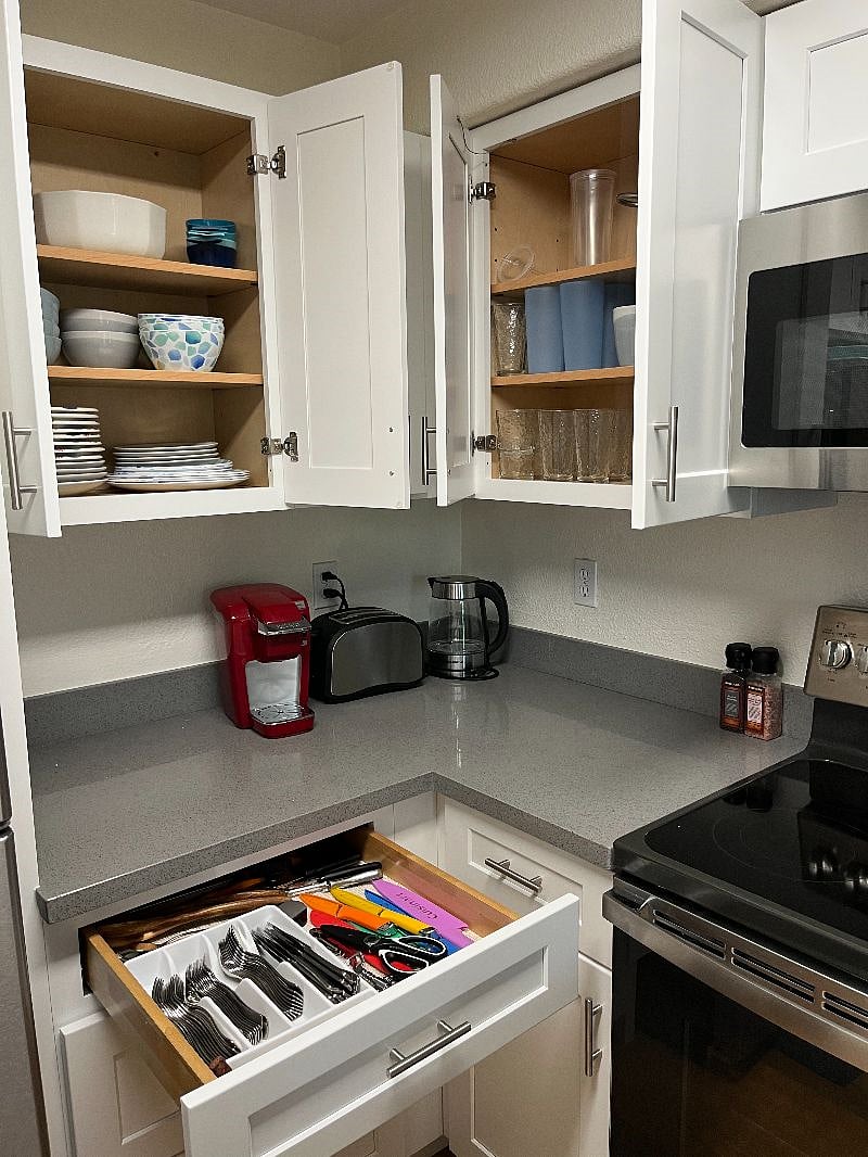 Fully-stocked kitchen with dishes, cookware, toaster, coffee maker, blender and air fryer.