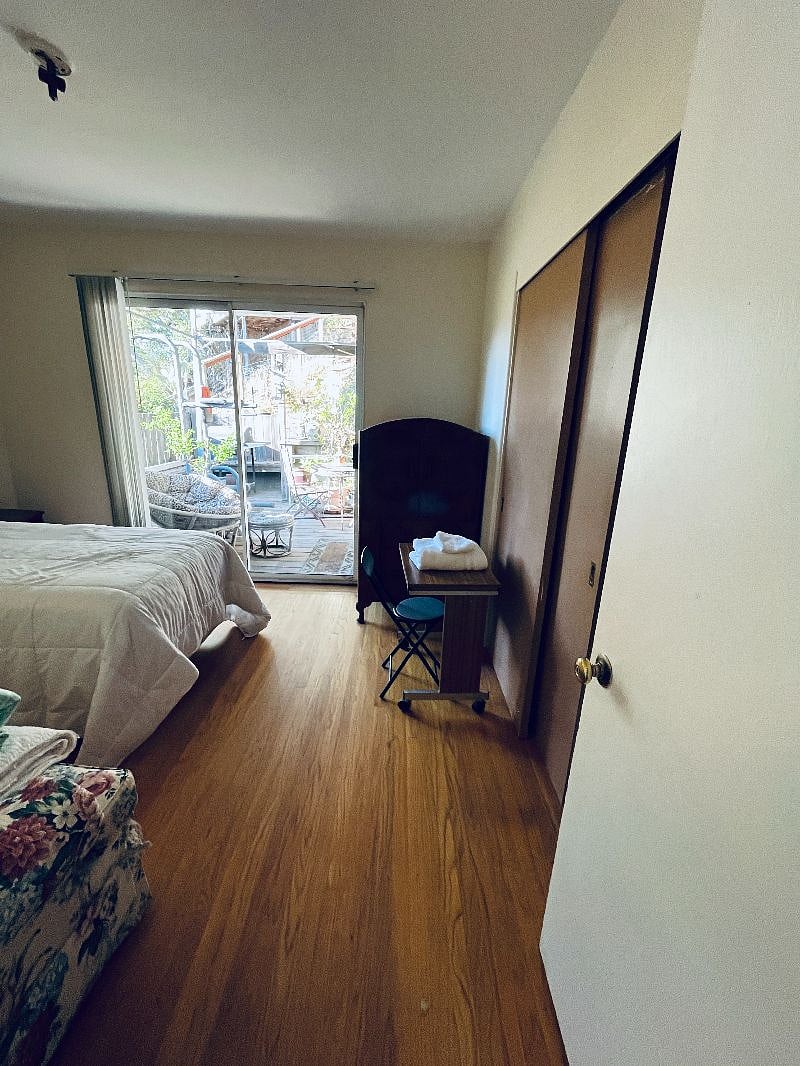 Bedroom with single bed, dresser, nightstand, small workspace, sofa, closet for clothes and light storage, sofa, ceiling light fan, lampshade, sliding door goes to deck area for this bedroom.