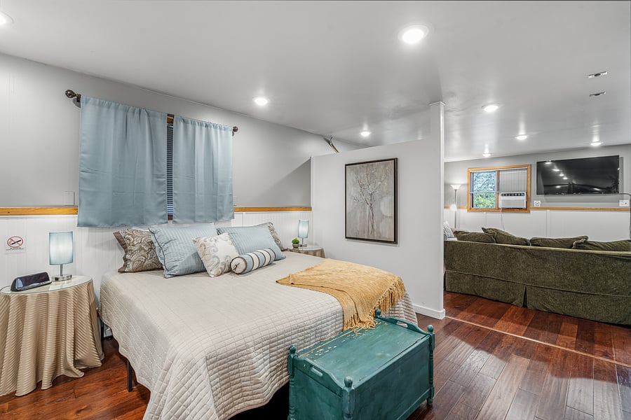 Bedroom has open floor plan and entry way looks into living area with flat screen TV.