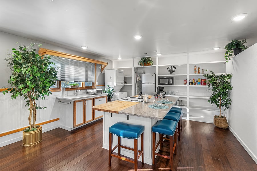 Kitchen has open floor plan with large island with eat-in bar area and stove-top. Plenty of shelving for storage and stacked washer/dryer.