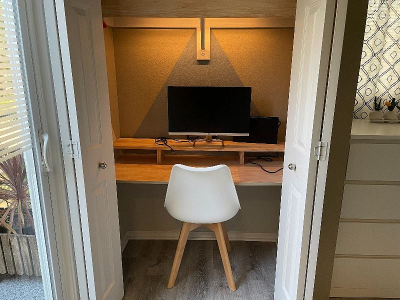 Mini office inside second bedroom closet with a 24" monitor